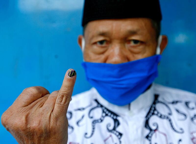 A voter wearing a protective mask shows his ink-stained finger after casting his vote during regional elections amid the coronavirus disease outbreak in Depok, on the outskirts of Jakarta, Indonesia. Reuters