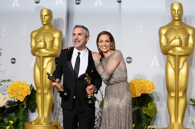 Presenter Angelina Jolie with Alfonso Cuaron, as he holds his award for best director for Gravity. AP 