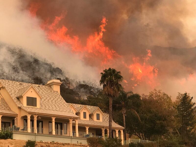 In this Thursday, Dec. 14, 2017, photo provided by the Santa Barbara County Fire Department, shows flames from a back firing operation underway rise behind a home off Ladera Ln near Bella Vista Drive in Santa Barbara, Calif. Red Flag warnings for the critical combination of low humidity and strong winds expired for a swath of Southern California at midmorning but a new warning was scheduled to go into effect Saturday in the fire area due to the predicted return of winds. The so-called Thomas Fire, the fourth-largest in California history, was 35 percent contained after sweeping across more than 394 square miles (1,020 sq. kilometers) of Ventura and Santa Barbara counties since it erupted Dec. 4 a few miles from Thomas Aquinas College. (Mike Eliason/Santa Barbara County Fire Department via AP)