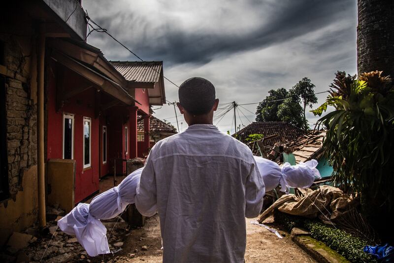 A man carries his dead son's body after an earthquake that killed hundreds in Cianjur, Indonesia on November 22. AFP