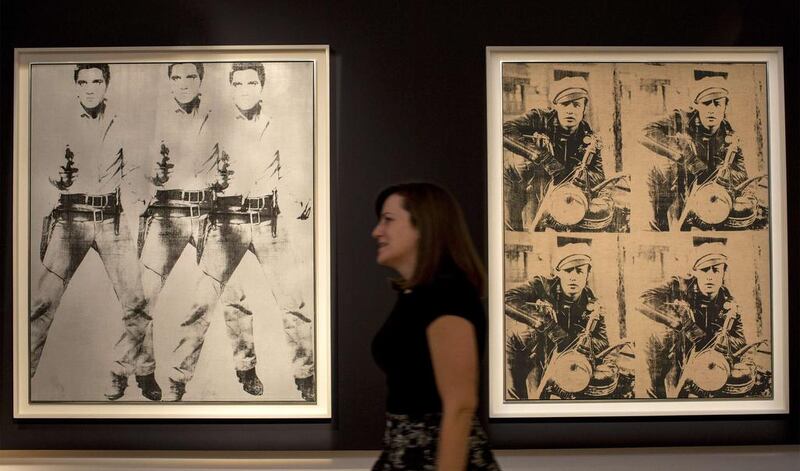 A woman walks between Triple Elvis and  Four Marlons by Andy Warhol during a media preview at Christie’s auction house in New York, October 31, 2014. Christie’s estimates its postwar and contemporary art auction will total more than $600 million, the highest pre-sale estimate ever for any single sale. Reuters