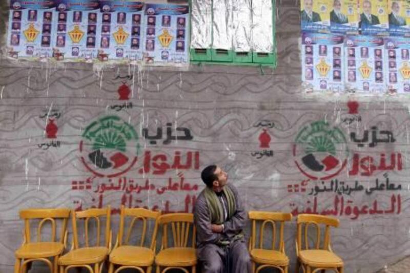 A man sitting under electoral posters for Salafi political party Al-Nour and the Muslim Brotherhood's Freedom and Justice Party, looks up at them outside a polling station during a second round of voting in parliamentary elections at a village in Beheira, 135 km (83 miles) north of Cairo, December 14, 2011. Egyptians voted on Wednesday in the second round of a parliamentary election, part of a lengthy transition to civilian rule after generals took charge following Hosni Mubarak's removal from office in February. REUTERS/Amr Abdallah Dalsh  (EGYPT - Tags: POLITICS ELECTIONS TPX IMAGES OF THE DAY) *** Local Caption ***  AMR078_EGYPT-ELECTI_1214_11.JPG
