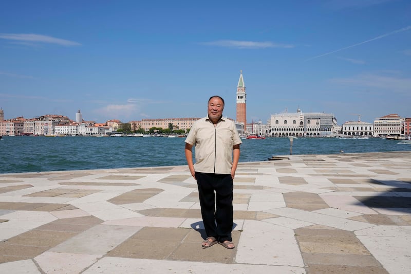 Ai Weiwei poses in front of Venice lagoon and San Marco's square in background.