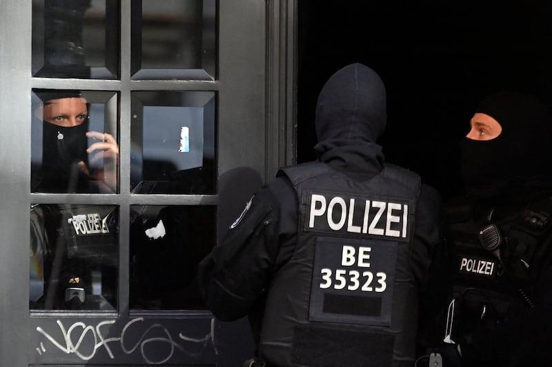 Masked police officers guard the entrance to a building at Wildenbruchstrasse in Berlin's Neukoelln district, during raids against organized clan criminality on February 18, 2021 in the German capital.  Several hundred police officers carried out a large-scale raid in Berlin and the federal state of Brandenburg on February 18, 2021 and detained two suspects following violent clashes between rival gangs in the German capital last autumn, according to police and state prosecutors. They added that the investigation also related to violent "clan clashes" in November 2020 between "members of a family of Arab origin and Russian nationals of Chechen background".
 / AFP / John MACDOUGALL
