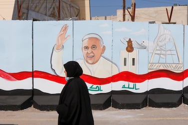 A woman walks past a mural of Pope Francis on the wall of a Baghdad church before his visit to Iraq. Reuters