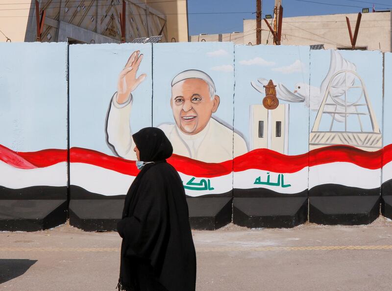 A woman walks near a mural of Pope Francis on the wall of a church upon his upcoming visit to Iraq, in Baghdad, Iraq February 22, 2021. REUTERS/Khalid al-Mousily     TPX IMAGES OF THE DAY