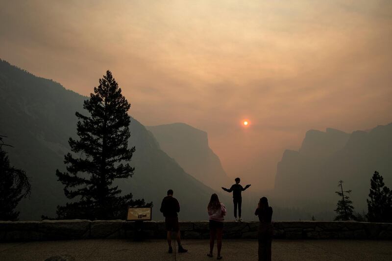 FILE - In this July 25, 2018 file photo, Hannah Whyatt poses for a friend's photo as smoke from the Ferguson fire fills Yosemite Valley in Yosemite National Park, Calif. Yosemite National Park could reopen its scenic valley and other areas Monday, Aug. 6, 2018, if conditions improve after a 12-day closure due to nearby wildfires. The parkâ€™s iconic cliffs have been shrouded in so much smoke that the air quality in Yosemite is currently worse than Beijing. (AP Photo/Noah Berger, File)