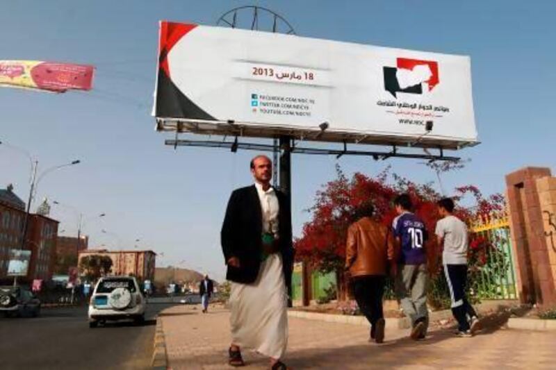 Yemenis walk under a billboard advertising their country’s UN-backed national dialogue conference in Sanaa.