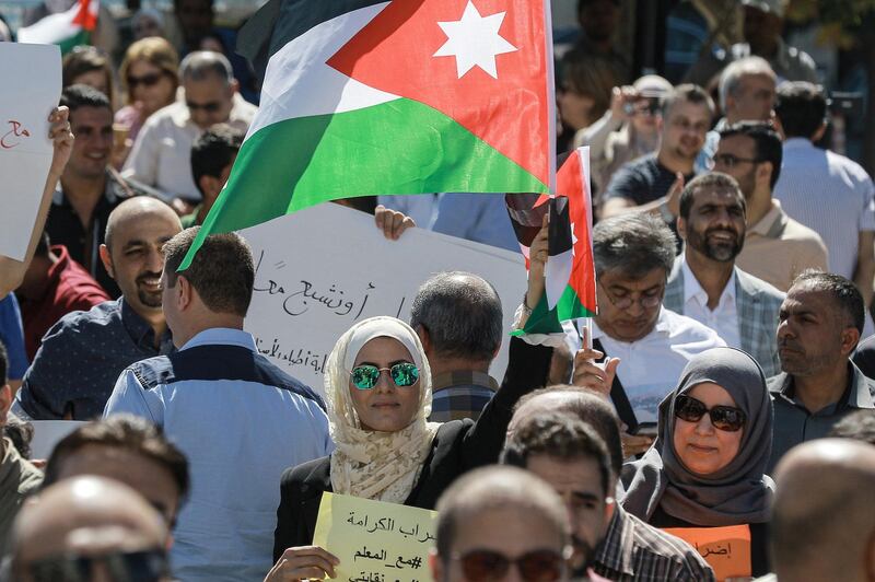 A woman raises a Jordanian national flag as she stands amidst public school teachers demonstrating and demanding pay raises, at the Professional Associations Complex in Jordan's capital Amman on October 3, 2019. (Photo by Khalil MAZRAAWI / AFP)