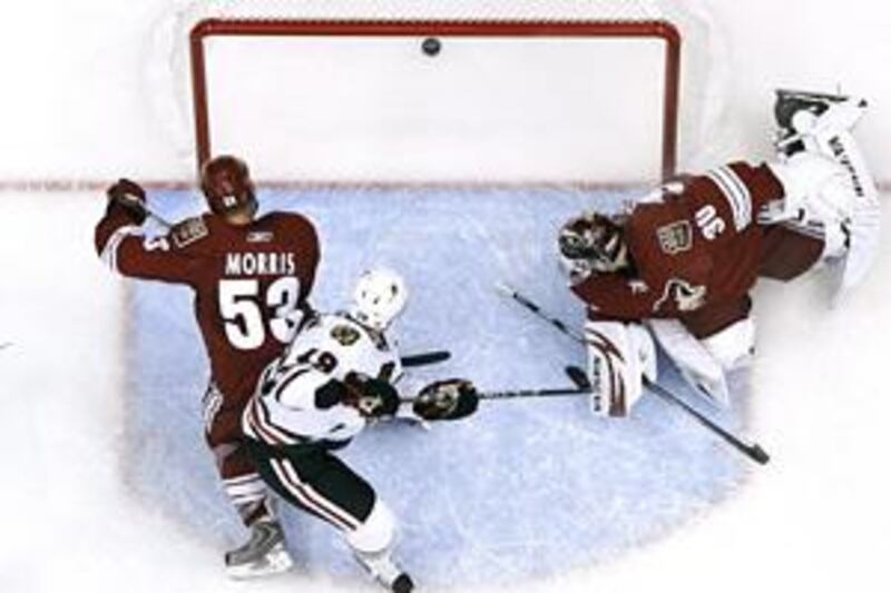 The Chicago Blackhawks' Jonathan Toews, centre, splits the Phoenix Coyotes' Derek Morris, 53, and Ilya Bryzgalov, 30, for a goal in Glendale, Arizona.