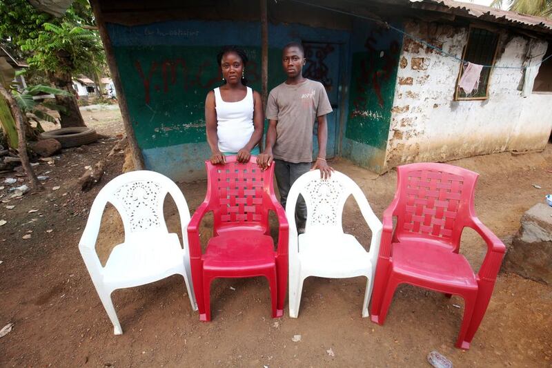 Lorpu Kollie and her brother Anthony pose for a family portrait at their home in the Pipeline community in a suburb of Monrovia, Liberia. The empty chairs are a representation of Lorpu’s and Anthony’s parents and other family members who died of the Ebola virus disease. Ahmed Jallanzo / EPA