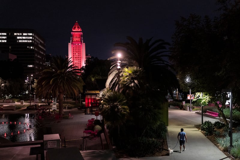 A man walks his dog as Los Angeles City Hall is illuminated in red and blue to honour Queen Elizabeth in Los Angeles. AP