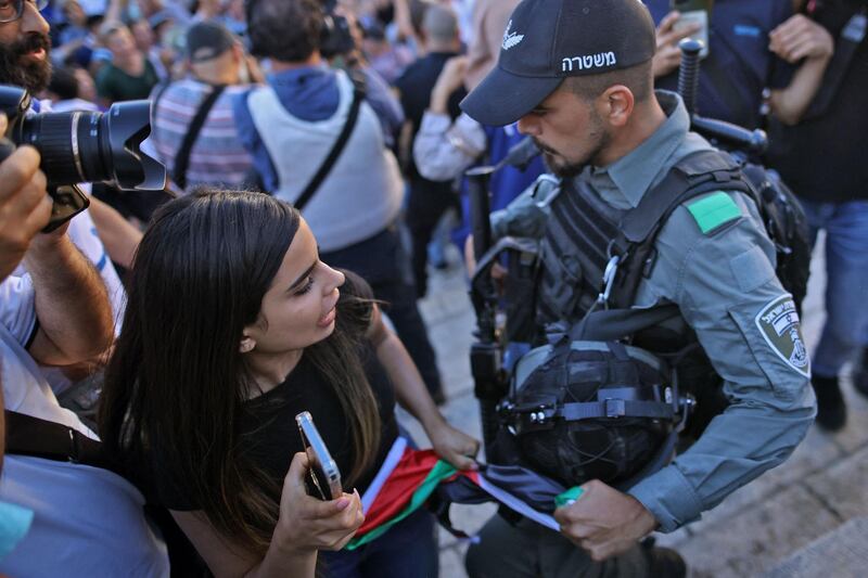 An Israeli security officer tries to take a Palestinian flag from a woman's hand. AFP