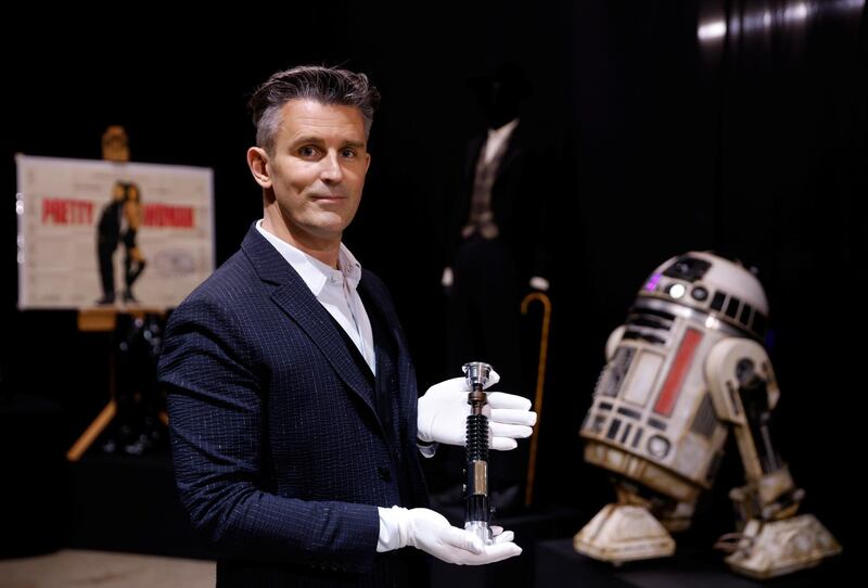 Stephen Lane, chief executive of Prop Store, poses for a photograph with Obi-Wan Kenobi's Hero Lightsaber from 'Star Wars: Revenge of the Sith', at a preview of a movie and TV memorabilia auction. Reuters
