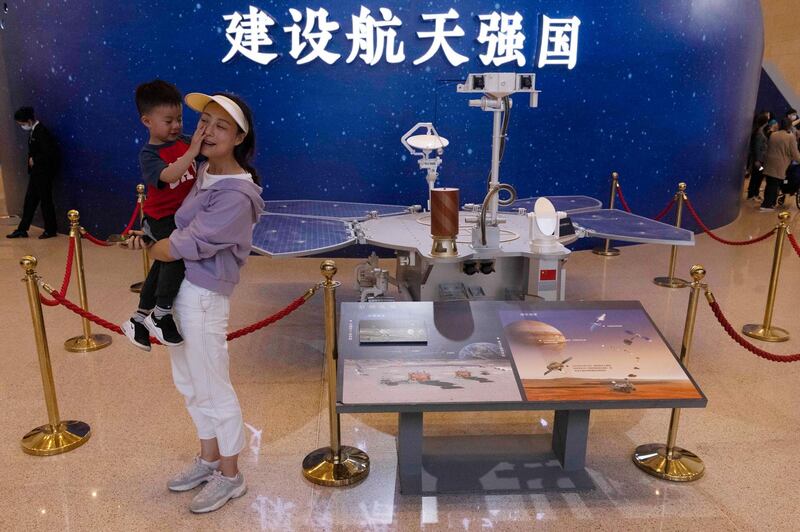 Visitors to an exhibition on China's space program pose for photos next to a life size model of the Chinese Mars rover Zhurong, named after the Chinese god of fire, at the National Museum in Beijing. AP Photo