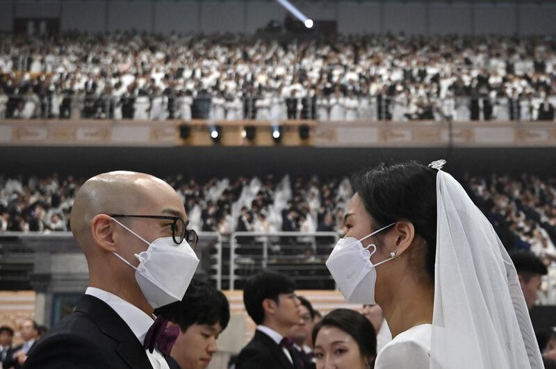 A couple wearing protective face masks attend a mass wedding ceremony organised by the Unification Church at Cheongshim Peace World Center in Gapyeong.  AFP