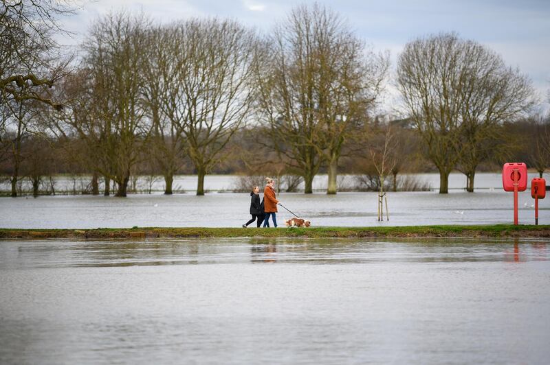 Dog walkers take a path between flooded fields and the River Great Ouse in Godmanchester. Getty Images