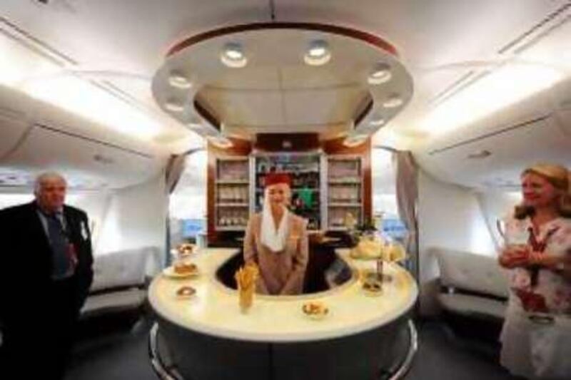 A flight attendant (C) gives a tour to journalists in the business class lounge aboard an Emirates Airline A380 on August 1, 2008. Emirates becomes the first commercial Airbus A380 jet to land in the United States at JFK International Airport in New York. The A380 is the world's largest airliner with 49 percent more floor space and 35 percent more seating than the previous largest aircraft.  AFP PHOTO/Stan HONDA *** Local Caption ***  990257-01-08.jpg *** Local Caption ***  990257-01-08.jpg