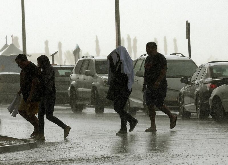 Pedestrians walk in the rain in Dubai. Satish Kumar / The National