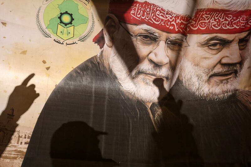 Supporters of pro-Iran factions gesture in front of a poster bearing an image of killed top Iranian commander Qassem Suleimani, right, and Iraqi commander Abu Mahdi Al Muhandis, in Baghdad's Tahrir square last week. AFP