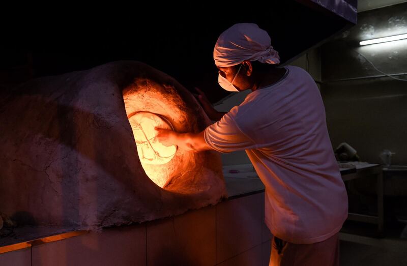 Indian baker prepares bread while wearing a protective mask during Ramadan in Bilad al Qadeem suburb of the Bahraini capital Manama.   AFP