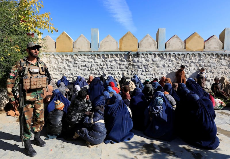 A member of the Afghan security forces watches next to family members of ISIS militants who surrendered to the Afghan government in Achin district of Nangarhar province, Afghanistan November 17, 2019. REUTERS/Parwiz