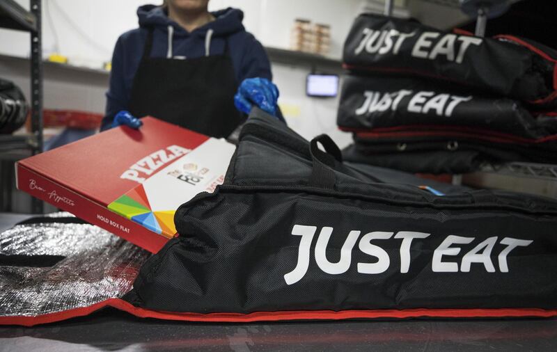 An employee places a pizza into a Just Eat Plc branded delivery bag in the kitchen of The Fat Pizza takeaway pizza restaurant in Southend-on-Sea, U.K., on Thursday, Dec 19, 2019. Takeaway.com raised its bid for Just Eat just minutes after Prosus NV upped its offer, intensifying a battle for ownership of the U.K. food-delivery firm. Photographer: Chris Ratcliffe/Bloomberg