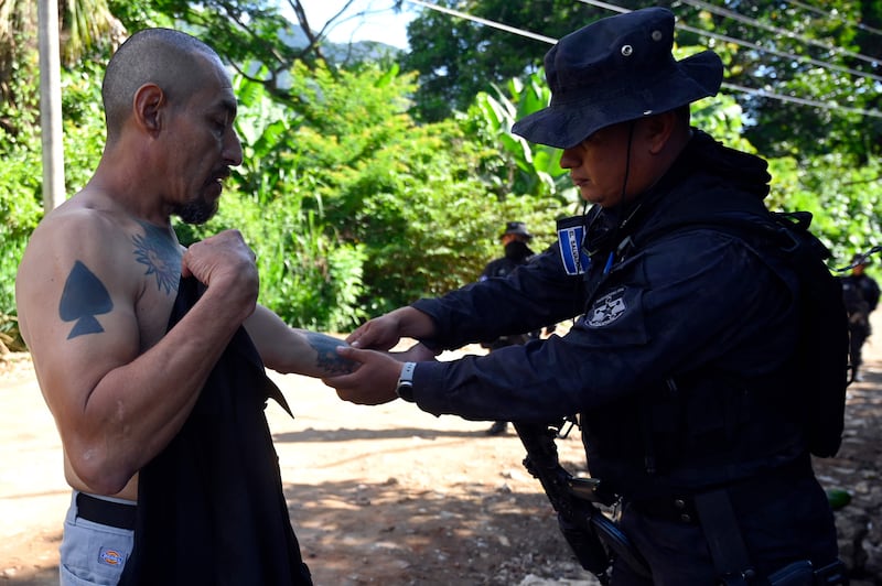 A police officer checks a man with tattoos during an operation to find gang members in Santa Ana. AFP