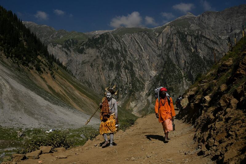 A Sadhu, or Hindu holy man, walks along a path next to another person during the pilgrimage to the Armarnath cave shrine in Indian-administered Kashmir. AFP