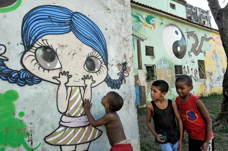 Children play next to a graffiti of street art in Havana, on July 12, 2017. / AFP PHOTO / YAMIL LAGE