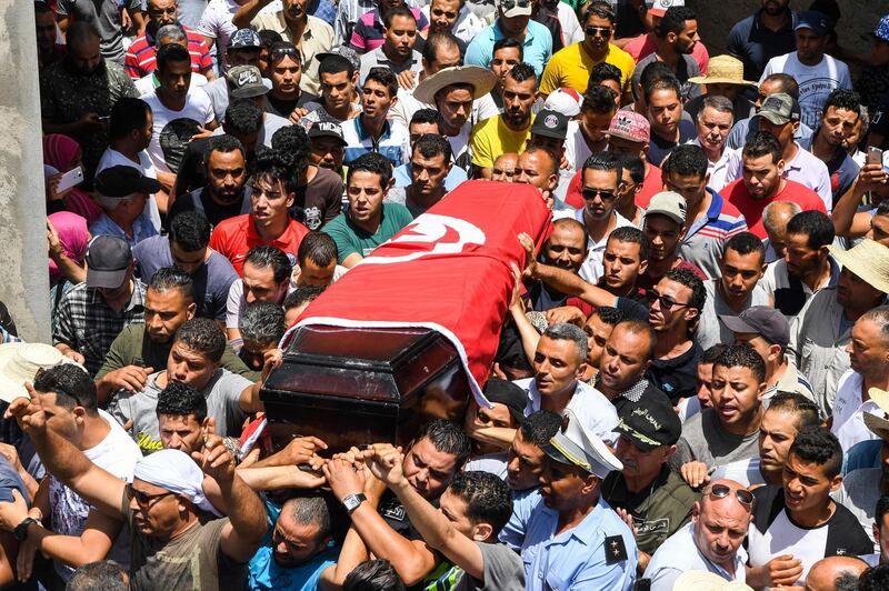 Mourners carry the coffin of killed Tunisian police officer Sgt. Arbi Guizani during a funerary procession in capital Tunis' northwestern suburb of Ettadhamen on July 9, 2018. Six members of Tunisia's security forces were killed on July 8 in a "terrorist attack" near the border with Algeria, the country's deadliest such incident in over two years. / AFP / FETHI BELAID
