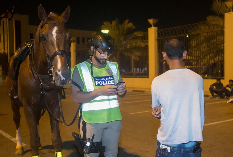 Abu Dhabi, United Arab Emirates- Police officer checking documents of suspicious people in Al Mushrif.  Leslie Pableo for The National for Haneen Dajani's story