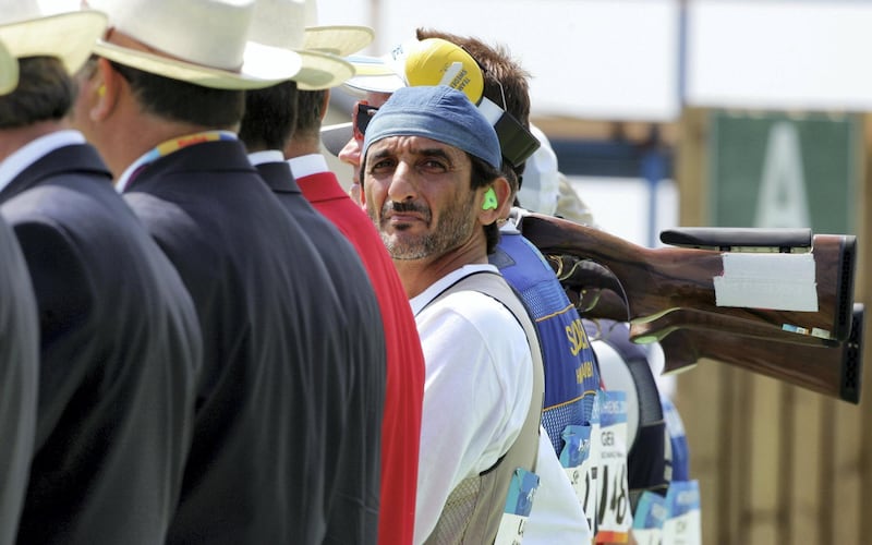 Sheikh Ahmed Al-Makoum of United Arab Emirates (C) looks at the scoreboard before the men's double trap final of the Athens 2004 Olympic Games in Athens, August 17, 2004. Almakyoum took gold with a score of 189. REUTERS/Guang Niu  GN/AA