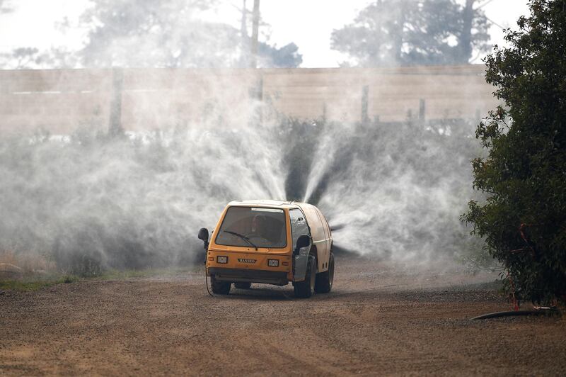 Property owners use a commercial watering machine to hose down their property as the Grose Valley Fire approaches Bilpin, Australia. Reuters