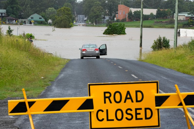 A car is parked near a flooded road at Windsor on the outskirts of Sydney, Australia. AP