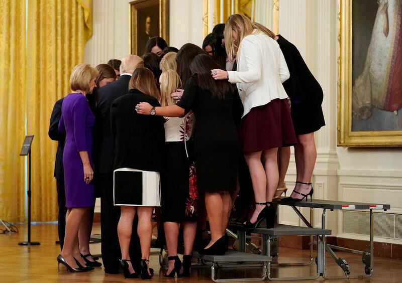 US President Donald Trump prays with the Oklahoma Women's Softball women team as he greets members of Championship NCAA teams at the White House in Washington. Joshua Roberts / Reuters
