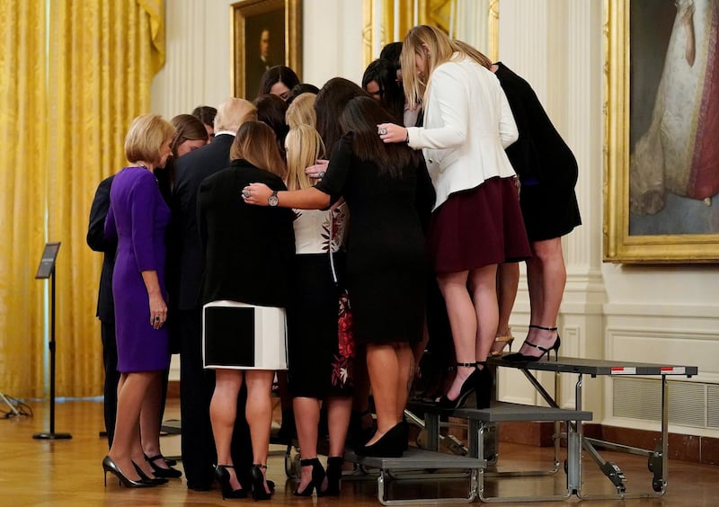 US President Donald Trump prays with the Oklahoma Women's Softball women team as he greets members of Championship NCAA teams at the White House in Washington. Joshua Roberts / Reuters