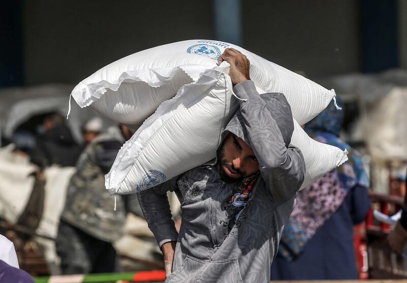 A Palestinian man carries sacks of flour received from a United Nations Relief and Works Agency distribution centre in the southern Gaza Strip refugee camp of Rafah. AFP