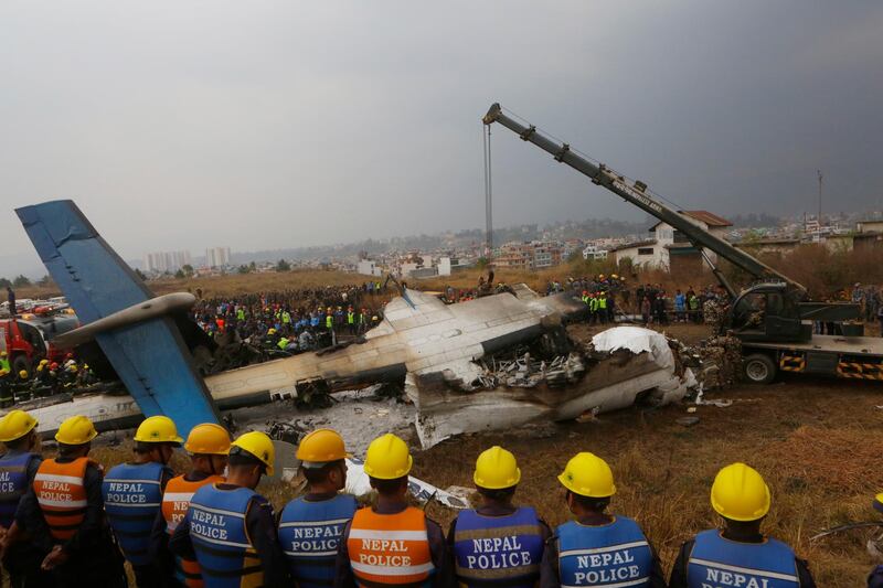 FILE- In this Monday, March 12, 2018 file photo, Nepalese rescuers and police are seen near the debris after a passenger plane from Bangladesh crashed at the airport in Kathmandu, Nepal.Survivors of this week's plane crash at Nepal's main airport said Wednesday that it was a miracle they survived an accident that killed 49 of the 71 people on board. (AP Photo/Niranjan Shreshta, File)