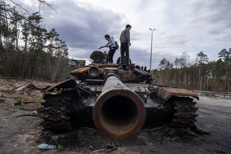 Local residents stand on top of a Russian tank on the outskirts of Kyiv. AP