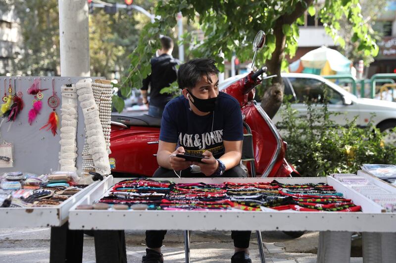 A street vendor wearing a mask to help prevent the spread of the coronavirus sits behind his stall on a sidewalk in downtown Tehran, Iran on September 20, 2020. AP Photo