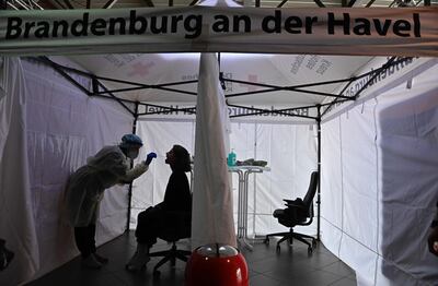 A member of the Deutsches Rotes Kreuz DRK explains a testing kit at the KVBB (Kassenaerztliche Vereinigung Berlin Brandenburg) Corona testing station inside the Metropolis at the film park Babelsberg in Potsdam, Eastern Germany, on November 16, 2020. / AFP / Tobias Schwarz
