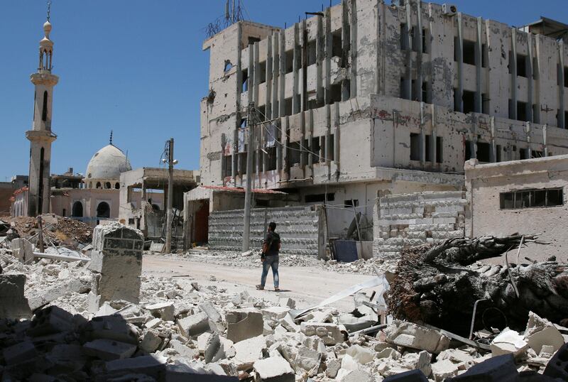 A Free Syrian Army fighter walks past damaged buildings inside a former Palestinian refugee camp in a rebel-held part of the southern city of Deraa, Syria weeks before the fragile ceasefire brokered by the US and Russia took effect in July 2017. Alaa Al-Faqir / Reuters