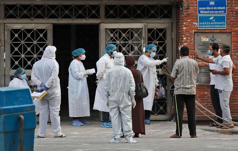 Health workers talk to attendants of a patient at a hospital meant for treating COVID-19 patients in New Delhi, India.  AP