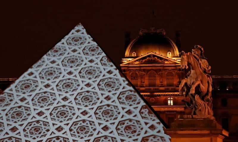 The dome pattern of the Louvre Abu Dhabi is projected onto the Louvre Pyramid in Paris on Wednesday night. Christian Hartmann / Reuters