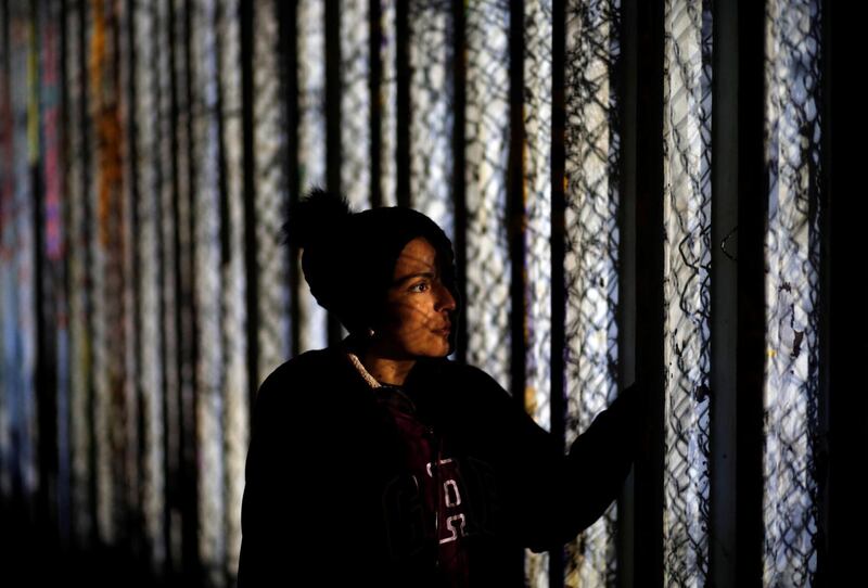 A migrant from Honduras looks through fence at a dead migrant who drowned trying to swim across to the United States from Mexico. Reuters