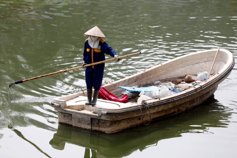 A woman collects garbage on To Lich river in Hanoi, Vietnam.   EPA