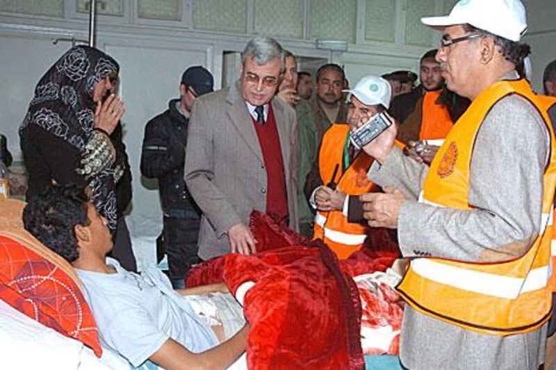 Arab League observers, wearing orange jackets, visit the wounded in the national hospital in Daraa, southern Syria, on Saturday. The observers are inspecting hotspots across the country.