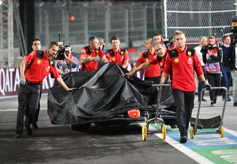 Ferrari crew return Carlos Sainz's car to the garage after it was damaged during first practice. AFP