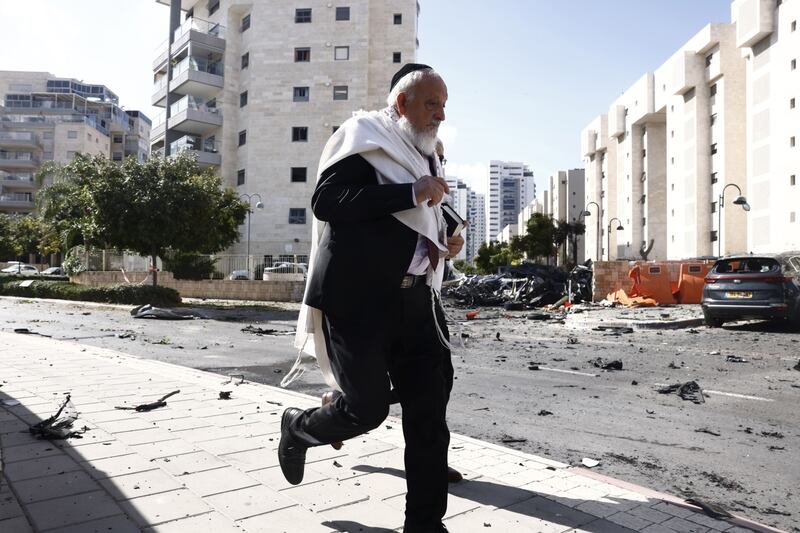 A man runs past cars damaged during a rocket attack in Ashkelon, Israel. Bloomberg